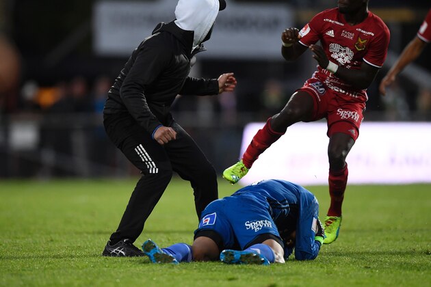 Ostersund's goalkeeper Aly Keita (C) remains on the ground after a masked soccer spectator (L) attacked him during a football match between Jonkoping Sodra and Ostersund in Jonkoping on August 15, 2016. / AFP / TT NEWS AGENCY / Mikael Fritzon / Sweden OUT (Photo credit should read MIKAEL FRITZON/AFP/Getty Images) Ostersund's goalkeeper Aly Keita (C) remains on the ground after a masked soccer spectator (L) attacked him during a football match between Jonkoping Sodra and Ostersund in Jonkoping on August 15, 2016. / AFP / TT NEWS AGENCY / Mikael Fritzon / Sweden OUT (Photo credit should read MIKAEL FRITZON/AFP/Getty Images)