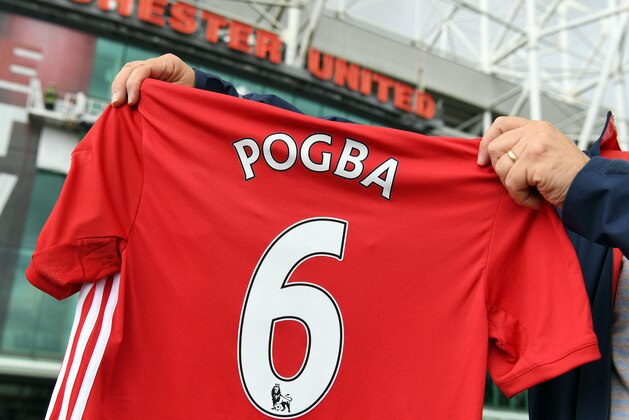 A man poses for pictures after purchasing a Manchester United shirt with the name and squad number of recent signing French midfielder Paul Pogba outside Old Traford in Manchester, north west England, on August 9, 2016.
The world record for a transfer fee was shredded Tuesday when French superstar Paul Pogba completed a sensational return to Manchester United from Juventus for 105 million euros ($116 million). / AFP / PAUL ELLIS        (Photo credit should read PAUL ELLIS/AFP/Getty Images)