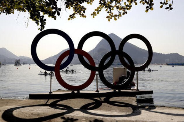 Athletes paddle to shore near the Olympic rings after the men's kayak double 1000m heat during the 2016 Summer Olympics in Rio de Janeiro, Brazil, Wednesday, Aug. 17, 2016. (AP Photo/Luca Bruno)