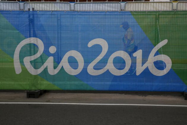 A volunteer walks behind a barrier printed with the Rio2016 logo inside Olympic Park ahead of the upcoming 2016 Summer Olympics in Rio de Janeiro, Brazil, Tuesday, Aug. 2, 2016. (AP Photo/Rebecca Blackwell)