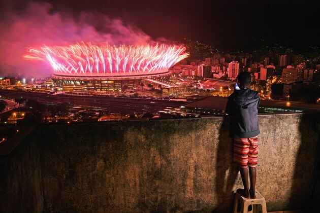 A boy from Mangueira favela watch fireworks over Maracana Stadium during the 2016 Olympics closing ceremony in Rio de Janeiro on August 21, 2016. / AFP / CARL DE SOUZA        (Photo credit should read CARL DE SOUZA/AFP/Getty Images)