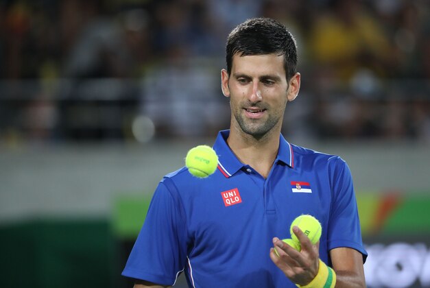 Aug 7, 2016; Rio de Janeiro, Brazil; Novak Djokovic (SRB) catches a ball during his match against Juan Martin Del Potro (ARG, not pictured) during the men's singles in the Rio 2016 Summer Olympic Games at Olympic Tennis Centre. Mandatory Credit: Jeff Swinger-USA TODAY Sports