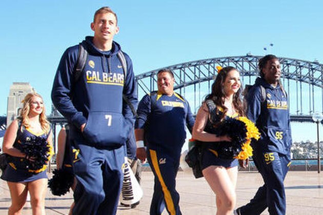 FILE - In this Aug. 23, 2016, file photo, the California football players Davis Webb, second left, and DeVante Wilson, right, walk with cheerleaders with the Harbour Bridge at the back in Sydney, Australia, ahead of their opening college football game of the season against the Hawaii Rainbow Warriors. Webb, a graduate transfer, has been named the starting quarterback for California for the 2016 season. (AP Photo/Rick Rycroft, file)