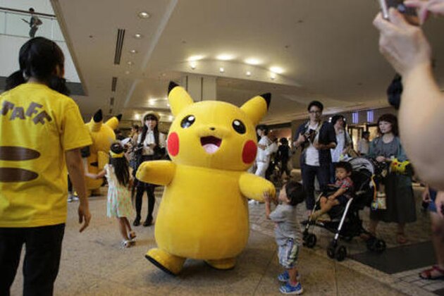A boy plays with Pokemon character Pikachu during a special gathering event of Pikachu at Minatomirai shopping district in Yokohama, near Tokyo, Wednesday, Aug. 10, 2016. (AP Photo/Shizuo Kambayashi)