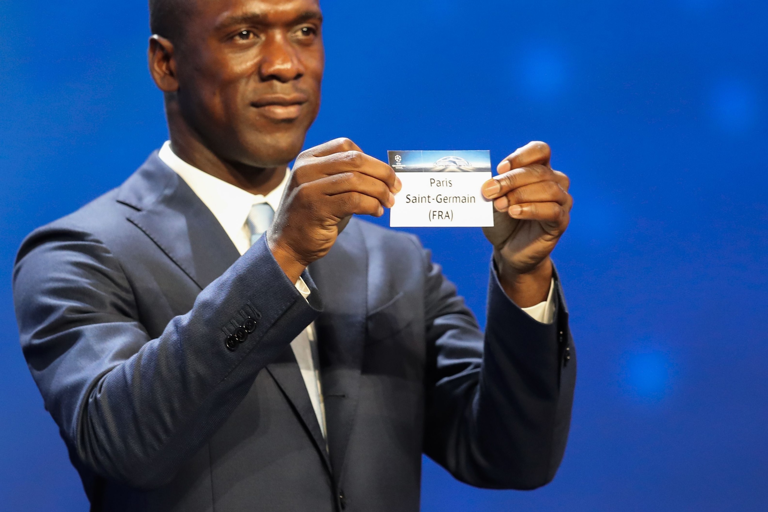 Dutch former football player Clarence Seedorf shows a piece of paper bearing the name of Paris-Saint-Germain during the UEFA Champions League Group stage draw ceremony, on August 25, 2016 in Monaco. / AFP / Valery HACHE        (Photo credit should read VALERY HACHE/AFP/Getty Images)