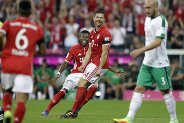 Bayern's Xabi Alonso, center, smiles after scoring his side's opening goal during the German Bundesliga soccer match between FC Bayern Munich and SV Werder Bremen at the Allianz Arena stadium in Munich, Germany, Friday, Aug. 26, 2016. (AP Photo/Matthias Schrader)