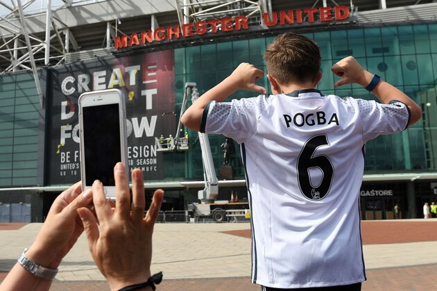 TOPSHOT - A boy poses for pictures after purchasing a Manchester United shirt with the name and squad number of recent signing French midfielder Paul Pogba outside Old Traford in Manchester, north west England, on August 9, 2016.
The world record for a transfer fee was shredded Tuesday when French superstar Paul Pogba completed a sensational return to Manchester United from Juventus for 105 million euros ($116 million). / AFP / PAUL ELLIS        (Photo credit should read PAUL ELLIS/AFP/Getty Images)