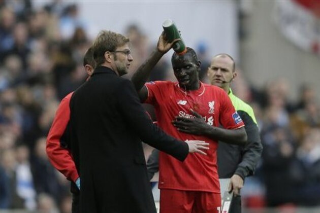 Liverpool's Mamadou Sakho tips a drink over his head as he speaks to his head coach Juergen Klopp before being taken off after a clash of heads with his teammate Emre Can during the English League Cup final soccer match between Liverpool and Manchester City at Wembley stadium in London, Sunday, Feb. 28, 2016. (AP Photo/Tim Ireland)