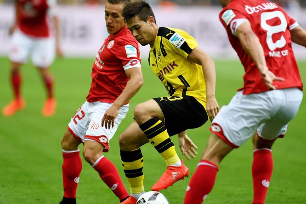 Dortmund's Portuguese defender Raphael Guerreiro (C) vies for the ball with Mainz' Argentinean striker Pablo De Blasis (L) during the German first division Bundesliga football match of Borussia Dortmund vs FSV Mainz 05 in Dortmund, western Germany, on August 27, 2016. / AFP / PATRIK STOLLARZ / RESTRICTIONS: DURING MATCH TIME: DFL RULES TO LIMIT THE ONLINE USAGE TO 15 PICTURES PER MATCH AND FORBID IMAGE SEQUENCES TO SIMULATE VIDEO. == RESTRICTED TO EDITORIAL USE == FOR FURTHER QUERIES PLEASE CONTACT DFL DIRECTLY AT + 49 69 650050
        (Photo credit should read PATRIK STOLLARZ/AFP/Getty Images)
