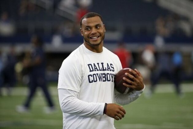 Dallas Cowboys quarterback Dak Prescott smiles as he talks with teammates on the field before a preseason NFL football game against the Houston Texans on Thursday, Sept. 1, 2016, in Arlington, Texas. (AP Photo/Ron Jenkins)