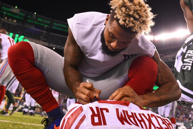 EAST RUTHERFORD, NJ - AUGUST 27:  Odell Beckham #13 of the New York Giants autographs his jersey prior to a jersey exchange with Darrelle Revis (not pictured) of the New York Jets following a preseason game at MetLife Stadium on August 27, 2016 in East Rutherford, New Jersey.  The Giants defeated the Jets 21-20.  (Photo by Rich Barnes/Getty Images)