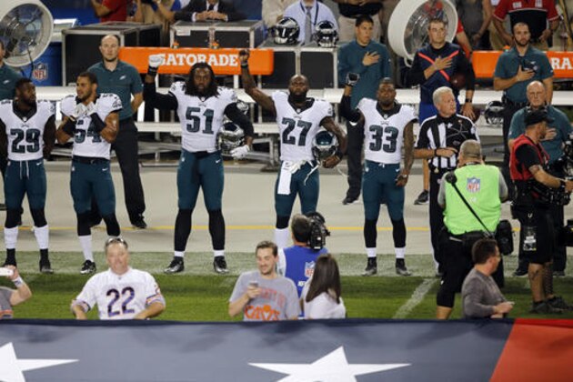 Philadelphia Eagles defensive end Steven Means (51), strong safety Malcolm Jenkins (27) and defensive back Ron Brooks (33) raise their arms during the national anthem before an NFL football game against the Chicago Bears, Monday, Sept. 19, 2016, in Chicago. (AP Photo/Kiichiro Sato)