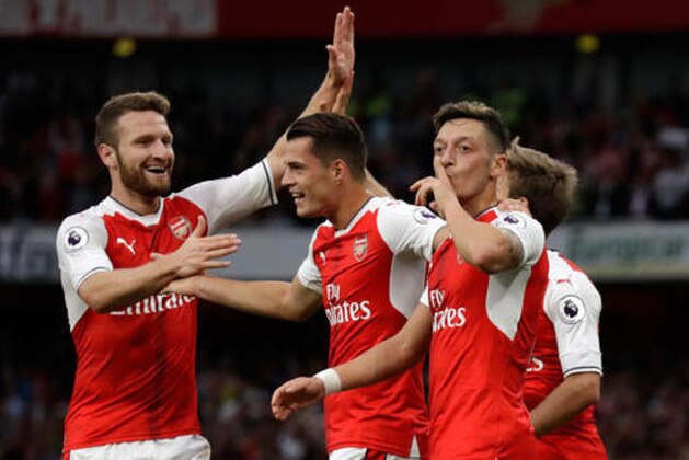Arsenal's Mesut Ozil, right, celebrates after scoring his side's third goal during the English Premier League soccer match between Arsenal and Chelsea at the Emirates Stadium in London, Saturday, Sept. 24, 2016. (AP Photo/Matt Dunham)