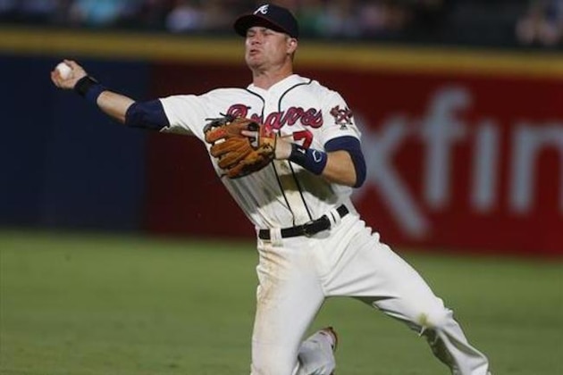 Atlanta Braves second baseman Gordon Beckham (7) makes a throwing error as he throws from his knees after fielding a ground ball by Colorado Rockies' DJ LeMahieu in the eighth inning of a baseball game Saturday, July 16, 2016, in Atlanta. A run scored on the play. (AP Photo/John Bazemore)