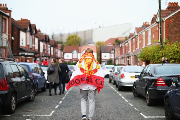 MANCHESTER, ENGLAND - OCTOBER 25: A Manchester United supporter holding the flag makes his way to the stadium prior to the Barclays Premier League match between Manchester United and Manchester City at Old Trafford on October 25, 2015 in Manchester, England.  (Photo by Clive Rose/Getty Images)