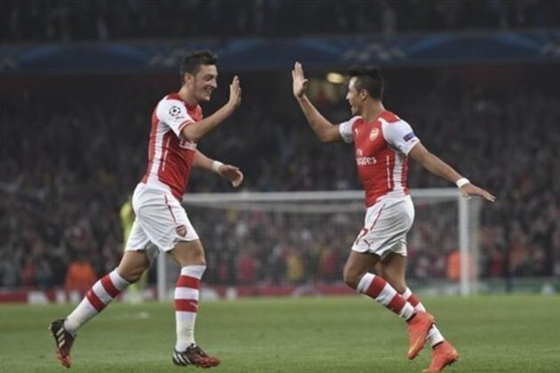 Arsenal's Alexis Sanchez, right, celebrates after scoring against Galatasaray with his teammate Mesut Ozil during the Champions League Group D soccer match between Arsenal  and Galatasaray , at the Emirates Stadium in London, on Wednesday, Oct 1, 2014. (AP Photo/ Tim Ireland)