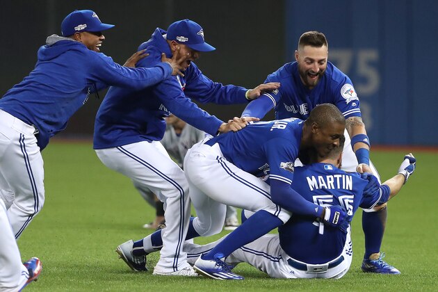 TORONTO, ON - OCTOBER 9: Russell Martin #55 of the Toronto Blue Jays is swarmed by teammates after the Toronto Blue Jays defeated the Texas Rangers 7-6 in ten innings during game three of the American League Division Series at Rogers Centre on October 9, 2016 in Toronto, Canada. (Photo by Tom Szczerbowski/Getty Images)