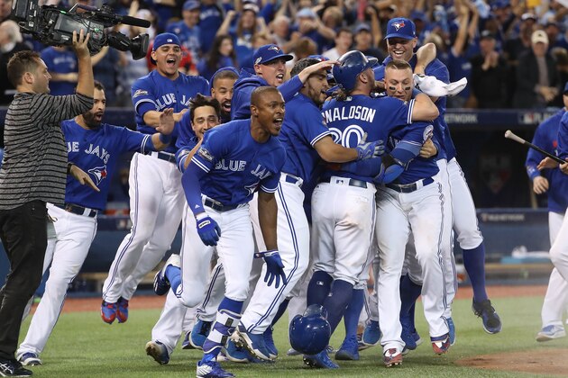 TORONTO, ON - OCTOBER 09: Josh Donaldson #20 of the Toronto Blue Jays is congratulated by teammates after scoring the game-winning run in the tenth inning during MLB game action against the Texas Rangers in game three of the American League Divison Series at Rogers Centre on October 9, 2016 in Toronto, Canada. (Photo by Tom Szczerbowski/Getty Images)