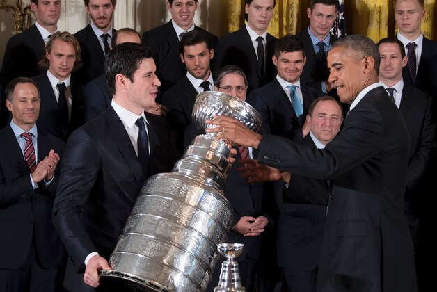 US President Barack Obama (R) gestures as Pittsburgh Penguins captain Sidney Crosby (L) picks up the Stanley Cup during an event at the White House in Washington, DC, October 6, 2016, honoring the Penguins 2016 Stanley Cup victory. / AFP / JIM WATSON        (Photo credit should read JIM WATSON/AFP/Getty Images)
