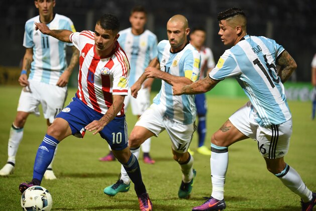 Paraguay's Derlis Gonzalez (L) vies for the ball with Argentina's Marcos Rojo (R) and Argentina's Javier Mascherano (C) during their Russia 2018 World Cup football qualifier match in Cordoba, Argentina, on October 11, 2016. / AFP / EITAN ABRAMOVICH        (Photo credit should read EITAN ABRAMOVICH/AFP/Getty Images)