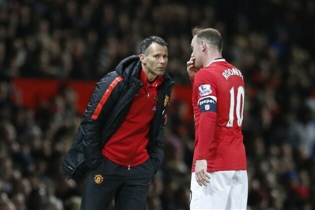 Manchester United’s assistant manager Ryan Giggs speaks to Manchester United’s Wayne Rooney on the sidelines during the English FA Cup quarterfinal soccer match between Manchester United and Arsenal at Old Trafford Stadium, Manchester, England, Monday March 9, 2015. (AP Photo/Jon Super)
