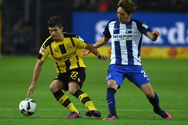 Dortmund's midfielder Christian Pulisic (L) and Hertha's Japanese midfielder Genki Haraguchi vie for the ball during the German first division Bundesliga football match between BVB Borussia Dortmund and Hertha BSC Berlin in Dortmund, western Germany on October 14, 2016. / AFP / PATRIK STOLLARZ / RESTRICTIONS: DURING MATCH TIME: DFL RULES TO LIMIT THE ONLINE USAGE TO 15 PICTURES PER MATCH AND FORBID IMAGE SEQUENCES TO SIMULATE VIDEO. == RESTRICTED TO EDITORIAL USE == FOR FURTHER QUERIES PLEASE CONTACT DFL DIRECTLY AT + 49 69 650050
        (Photo credit should read PATRIK STOLLARZ/AFP/Getty Images)