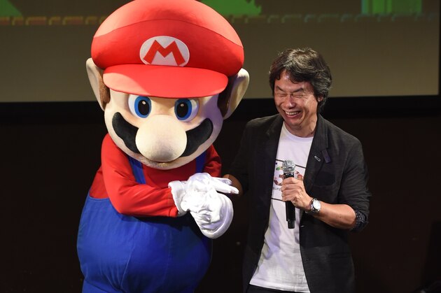 Nintendo's game creator Shigeru Miyamoto (R) poses with his character 'Super Mario' (L) during a live performance of the most well-known Mario music to mark the game's 30th anniversary in Tokyo on September 13, 2015. Nintendo celebrated the 30th anniversary of Super Mario, one of the best-known characters in video game history, at the event in Tokyo where artists played his theme music to fans dressed up as the hyperactive plumber.      AFP PHOTO / TOSHIFUMI KITAMURA        (Photo credit should read TOSHIFUMI KITAMURA/AFP/Getty Images)