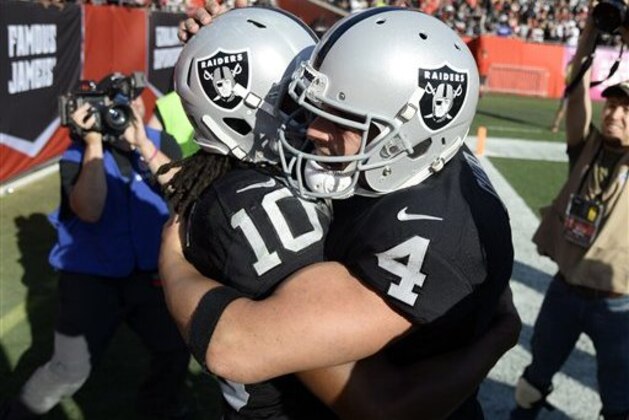 Derek Carr (4), de los Raiders de Oakland, abraza al receptor Seth Roberts, quien anotó en el tiempo extra del partido ante los Buccaneers de Tampa Bay, el domingo 30 de octubre de 2016 (AP Foto/Jason Behnken)