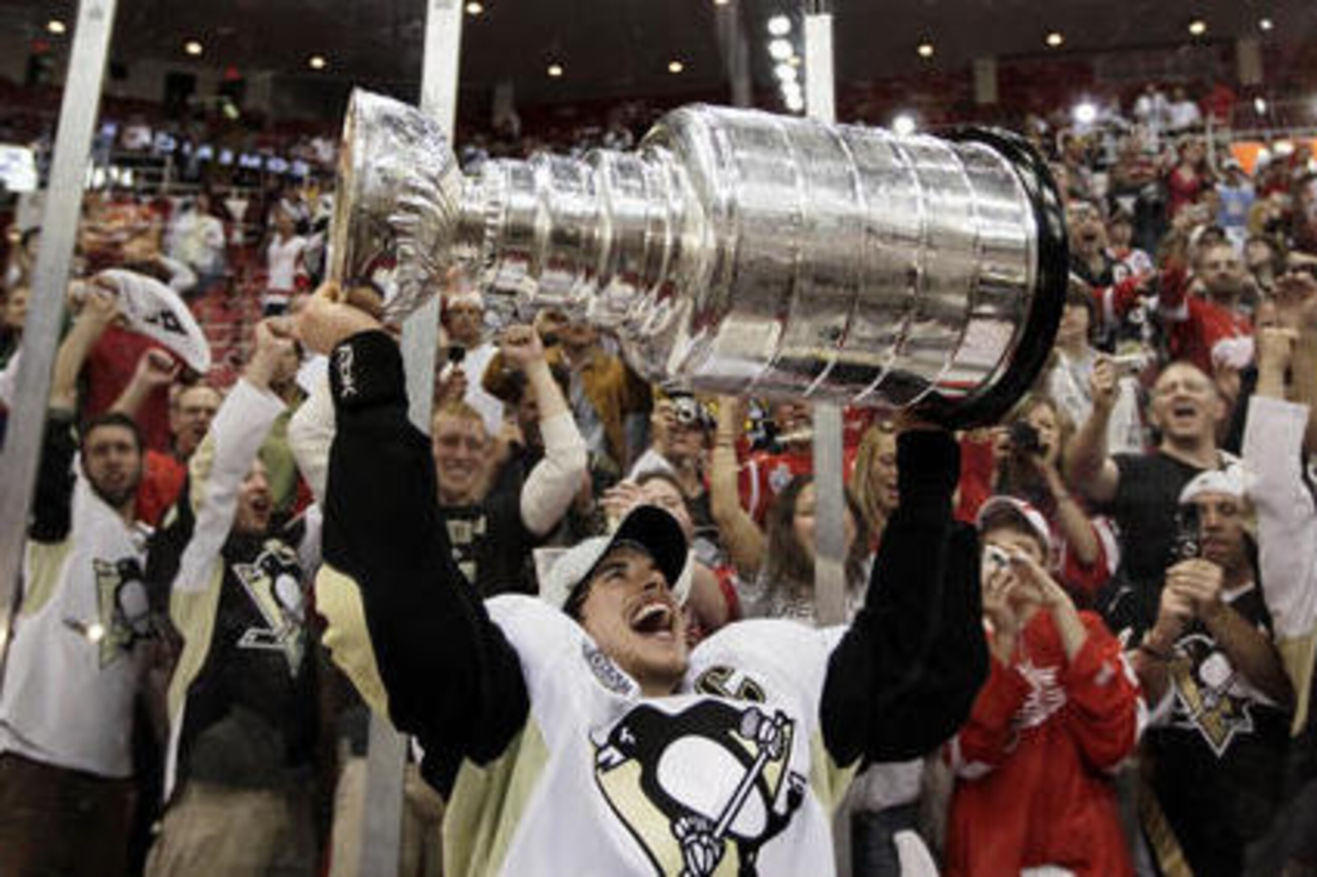 FILE - In this June 12, 2009, file photo,Pittsburgh Penguins' captain Sidney Crosby raises the Stanley Cup after the Penguins beat the Detroit Red Wings 2-1 to win Game 7 of the NHL hockey Stanley Cup finals in Detroit. The Steelers won their record sixth Super Bowl title and second in four seasons, 27-23 over the Arizona Cardinals. The Penguins snared their third title by winning a seven-game Stanley Cup finals over the Detroit Red Wings. (AP Photo/Paul Sancya, File)