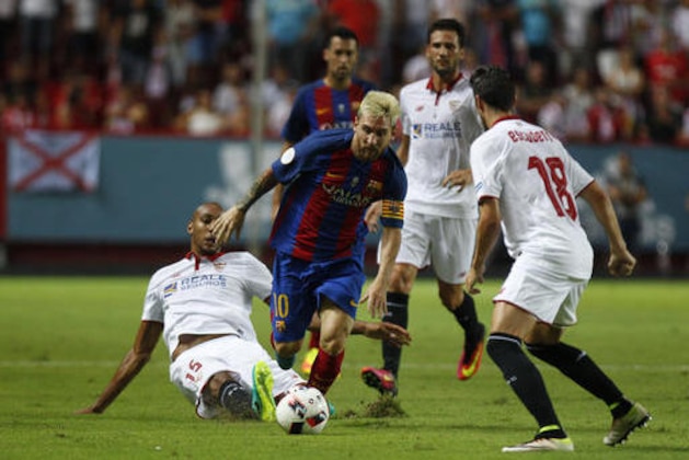 Sevilla's Steven N'Zonzi, left tries to tackle Barcelona's Lionel Messi during the Spanish Super Cup first-leg soccer match at Ramon Sanchez-Pizjuan stadium in Seville, Spain, Sunday, Aug. 14, 2016. (AP Photo/Antonio Pizarro)