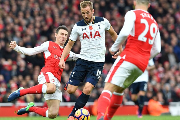 Arsenal's French defender Laurent Koscielny (L) tackles Tottenham Hotspur's English striker Harry Kane (C) during the English Premier League football match between Arsenal and Tottenham Hotspur at the Emirates Stadium in London on November 6, 2016. 
Koscielny received a yellow card for the challenge. / AFP / BEN STANSALL / RESTRICTED TO EDITORIAL USE. No use with unauthorized audio, video, data, fixture lists, club/league logos or 'live' services. Online in-match use limited to 75 images, no video emulation. No use in betting, games or single club/league/player publications.  /         (Photo credit should read BEN STANSALL/AFP/Getty Images)