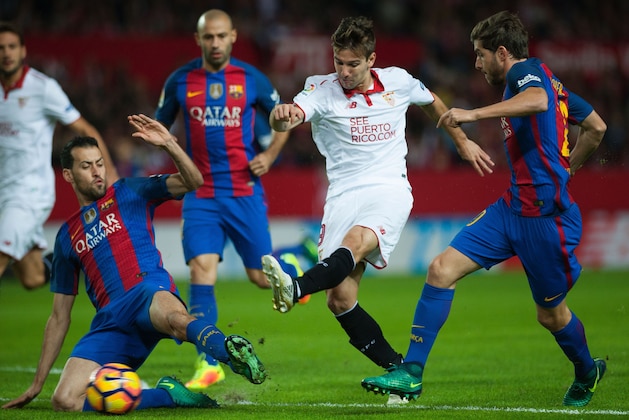 Barcelona's midfielder Sergio Busquets (L) and midfielder Sergi Roberto (R) vies with Sevilla's Argentinian forward Luciano Vietto during the Spanish league football match Sevilla FC vs FC Barcelona at the Ramon Sanchez Pizjuan stadium in Sevilla on November 6, 2016. / AFP / JORGE GUERRERO        (Photo credit should read JORGE GUERRERO/AFP/Getty Images)