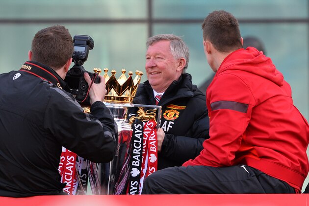 Retiring iconic Manchester United manager Alex Ferguson (C) holds the Premier League trophy as he boards the champions' bus outside Old Trafford Stadium in Manchester, north west England, on May 13, 2013 as the team begins their victory parade to celebrate winning the Premier League title for the 13th time. AFP PHOTO/PAUL ELLIS        (Photo credit should read PAUL ELLIS/AFP/Getty Images)