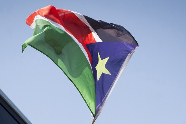 A South Sudanese refugee waves his national flag as they board a bus taking them to Ben Gurion International airport, near Tel Aviv, where they will be deported to South Sudan, on June 17, 2012.  Israel was preparing to fly home about 120  illegal immigrants from South Sudan, the first wave in the planned expulsion of tens of thousands of Africans, officials said. AFP PHOTO/OREN ZIV =ISRAEL OUT=        (Photo credit should read OREN ZIV/AFP/GettyImages)