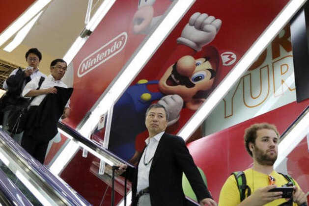 FILE - In this July 13, 2015, file photo, shoppers ride on an escalator under Nintendo's Super Mario characters at an electronics store in Tokyo. Nintendo Co. is ending sales in Japan of its Wii U home console “soon,” although it’s not saying exactly when, and similar announcements are expected in other regions. The Wii U, which went on sale from late 2012, is being replaced by Switch, set to go on sale globally in March 2017. Nintendo says it will show it to reporters in Japan on Jan. 13. (AP Photo/Koji Sasahara, File)