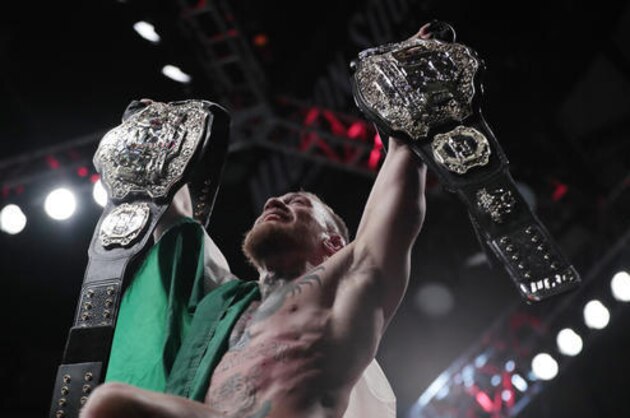 Conor McGregor holds up his title belts after he defeated Eddie Alvarez during a lightweight title mixed martial arts bout at UFC 205, early Sunday, Nov. 13, 2016, at Madison Square Garden in New York. (AP Photo/Julio Cortez)