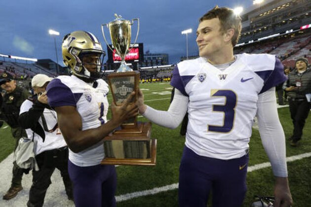 Washington quarterback Jake Browning, right, hands the Apple Cup trophy to wide receiver John Ross, left, as they walk off the field after Washington beat Washington State 45-17 in an NCAA college football game, Friday, Nov. 25, 2016, in Pullman, Wash. (AP Photo/Ted S. Warren)