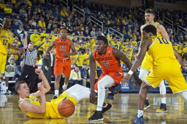 Michigan guard Duncan Robinson (22) reacts after drawing a charging penalty from Virginia Tech guard Chris Clarke (15) under the basket during the first half of an NCAA college basketball game at Crisler Center in Ann Arbor, Mich., Wednesday, Nov. 30, 2016. (AP Photo/Tony Ding)