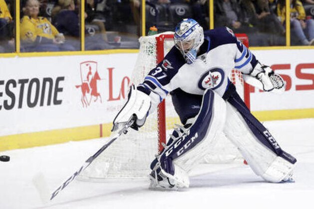 Winnipeg Jets goalie Connor Hellebuyck reaches for the puck during the second period of an NHL hockey game against the Nashville Predators Friday, Nov. 25, 2016, in Nashville, Tenn. (AP Photo/Mark Humphrey)