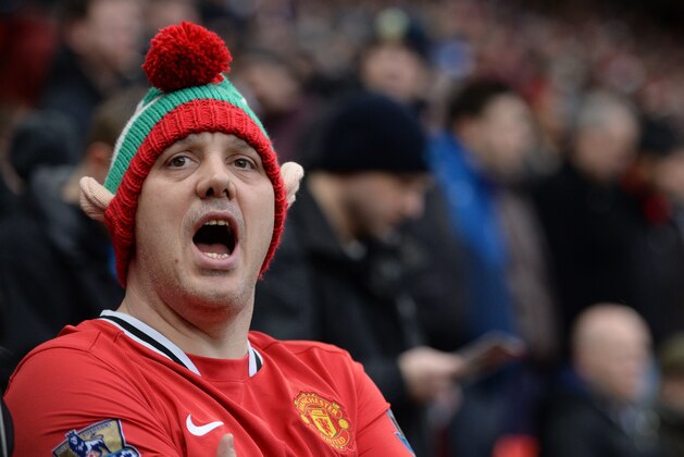 A Manchester United supporter wearing a festive hat singing in the stands ahead of the English Premier League football match between Manchester United and Liverpool at Old Trafford in Manchester, north west England, on December 14, 2014. AFP PHOTO / OLI SCARFF  RESTRICTED TO EDITORIAL USE. No use with unauthorized audio, video, data, fixture lists, club/league logos or live services. Online in-match use limited to 45 images, no video emulation. No use in betting, games or single club/league/player publications.        (Photo credit should read OLI SCARFF/AFP/Getty Images)