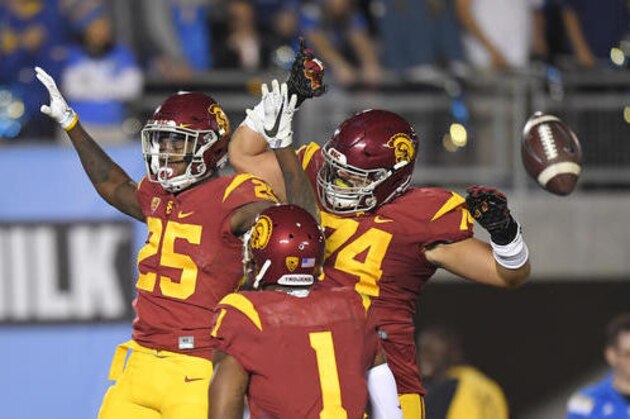 Southern California running back Ronald Jones II, left, celebrates with center Nico Falah, right, and wide receiver Darreus Rogers after running 60 years for a touchdown during the first half of an NCAA college football game against UCLA, Saturday, Nov. 19, 2016, in Pasadena, Calif. (AP Photo/Mark J. Terrill)