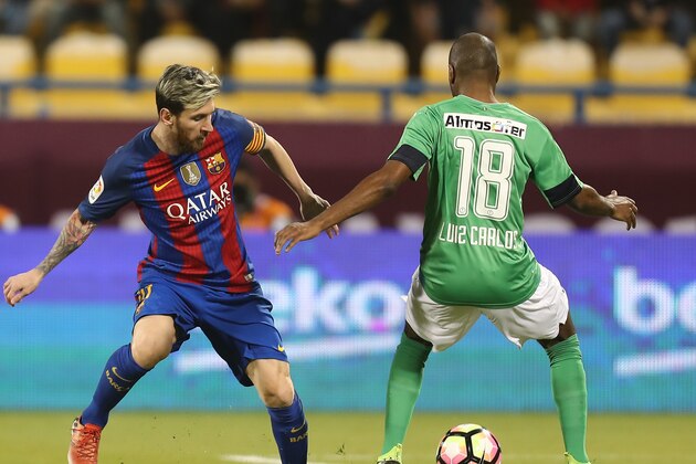 FC Barcelona's Lionel Messi (L) vies with Al-Ahli's Luiz Carlos during a friendly football match between FC Barcelona and Saudi Arabia's Al-Ahli FC on December 13, 2016 in the Qatari capital Doha. 
Barcelona play Saudi champions Al-Ahli in a friendly in Doha, the Spanish club's last major obligation of its four year shirt sponsorship deal with Qatar Airways.

 / AFP / KARIM JAAFAR        (Photo credit should read KARIM JAAFAR/AFP/Getty Images)