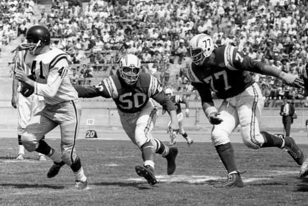 San Diego Chargers linebacker Chuck Allen (50) and defensive tackle Ernie Ladd (77) chase New York Titans fullback Charlie Flowers (41) during a 40-14 Chargers victory on September 16, 1962, at Balboa Stadium in San Diego, California. (Photo by Charles Aqua Viva/Getty Images)