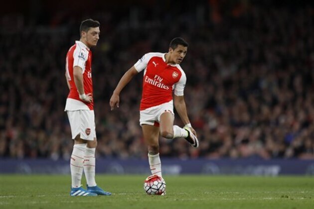 Arsenal's Mesut Ozil, left, and Alexis Sanchez stand together as Sanchez waits to take a freekick from which he scored their second goal during the English Premier League soccer match between Arsenal and West Bromwich Albion at the Emirates Stadium in London, Thursday, April 21, 2016.  (AP Photo/Matt Dunham)