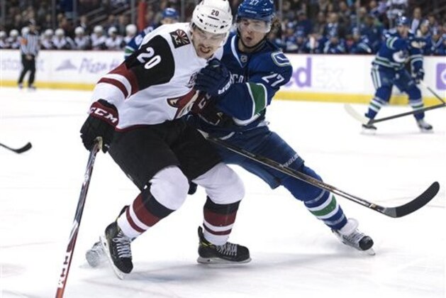 Vancouver Canucks defenseman Ben Hutton (27) fights for control of the puck with Arizona Coyotes center Dylan Strome (20) during the first period of an NHL hockey game Thursday, Nov. 17, 2016, in Vancouver, British Columbia. (Jonathan Hayward/The Canadian Press via AP)