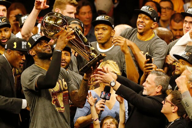 TOPSHOT - Cleveland Cavaliers forward LeBron James hoists the Larry O'Brien trophy after defeating the Golden State Warriors to win the NBA Finals on June 19, 2016 in Oakland, California.
Powered by an amazing effort from LeBron James, the Cleveland Cavaliers completed the greatest comeback in NBA Finals history, dethroning defending champion Golden State 93-89 to capture their first NBA title. The Cavaliers won the best-of-seven series 4-3 to claim the first league crown in their 46-season history and deliver the first major sports champion to Cleveland since the 1964 NFL Browns, ending the longest such title drought for any American city.
 / AFP / Beck Diefenbach        (Photo credit should read BECK DIEFENBACH/AFP/Getty Images)