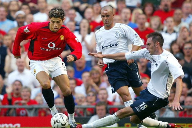 Manchester United's Cristiano Ronaldo (L) takes the ball past Stylianos Giannakopoulos (back) and Nicky Hunt (R) of Bolton Wanderers during the first Premiership match of the season at Old Trafford in Manchester, 16 August 2003. Ronaldo, making his debut, won a penalty and played sensationally after coming on as a substitute. Manchester United won the game 4-0. AFP PHOTO Adrian DENNIS  (Photo credit should read ADRIAN DENNIS/AFP/Getty Images)