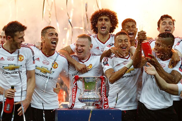 Manchester United's players (L-R) Manchester United's English midfielder Michael Carrick, Manchester United's English defender Chris Smalling, Manchester United's English striker Wayne Rooney, Manchester United's Belgian midfielder Marouane Fellaini, Manchester United's English midfielder Jesse Lingard, Manchester United's English striker Marcus Rashford, Manchester United's Ecuadorian midfielder Antonio Valencia and Manchester United's Matteo Darmian celebrate on the pitch with the trophy after their victory after extra time in the English FA Cup final football match between Crystal Palace and Manchester United at Wembley stadium in London on May 21, 2016.
Manchester United won the game 2-1, after extra time. / AFP / IAN KINGTON / NOT FOR MARKETING OR ADVERTISING USE / RESTRICTED TO EDITORIAL USE        (Photo credit should read IAN KINGTON/AFP/Getty Images)