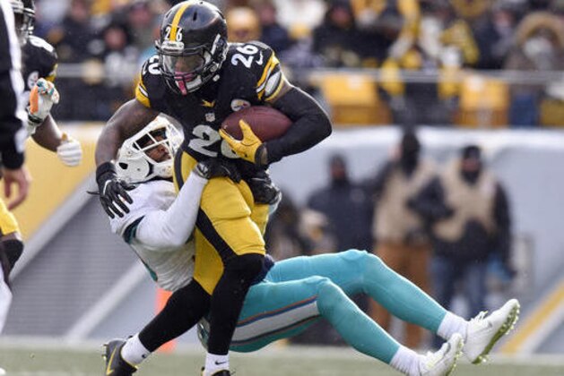 Pittsburgh Steelers running back Le'Veon Bell (26) runs through a tackle by Miami Dolphins free safety Bacarri Rambo during the first half of an AFC wild-card NFL football game in Pittsburgh, Sunday, Jan. 8, 2017. (AP Photo/Don Wright)