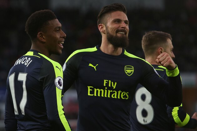 Arsenal's Nigerian striker Alex Iwobi (l) celebrates his team's second goal with Arsenal's French striker Olivier Giroud (C), after his shot was defelected into goal off Swansea City's English midfielder Jack Cork (unseen) during the English Premier League football match between Swansea City and Arsenal at The Liberty Stadium in Swansea, south Wales on January 14, 2017. / AFP / Geoff CADDICK / RESTRICTED TO EDITORIAL USE. No use with unauthorized audio, video, data, fixture lists, club/league logos or 'live' services. Online in-match use limited to 75 images, no video emulation. No use in betting, games or single club/league/player publications. / (Photo credit should read GEOFF CADDICK/AFP/Getty Images) Arsenal's Nigerian striker Alex Iwobi (l) celebrates his team's second goal with Arsenal's French striker Olivier Giroud (C), after his shot was defelected into goal off Swansea City's English midfielder Jack Cork (unseen) during the English Premier League football match between Swansea City and Arsenal at The Liberty Stadium in Swansea, south Wales on January 14, 2017. / AFP / Geoff CADDICK / RESTRICTED TO EDITORIAL USE. No use with unauthorized audio, video, data, fixture lists, club/league logos or 'live' services. Online in-match use limited to 75 images, no video emulation. No use in betting, games or single club/league/player publications. / (Photo credit should read GEOFF CADDICK/AFP/Getty Images)